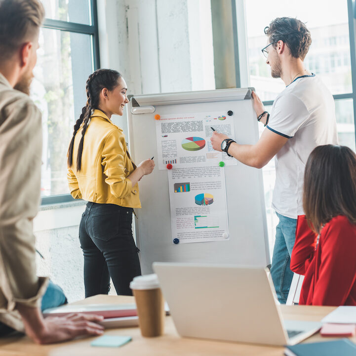 Professional business colleagues men and women discussing charts in modern office